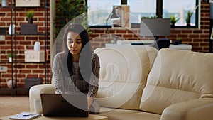 Teleworker sitting on couch, focused on finishing tasks in personal office