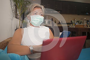 Teleworking during covid-19 virus quarantine - attractive and busy woman in protective mask remote working with laptop computer