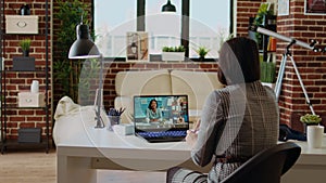 Teleworking team leader in cozy apartment discussing with coworkers in videocall