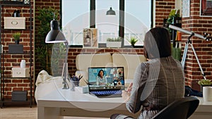 Teleworking team leader in cozy apartment discussing with coworkers in videocall