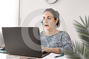 Teleworking woman with a headphones and a laptop computer at home in the livingroom. Telework concept and empty copy space