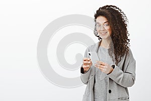 Tell me your phone number. Portrait of stylish good-looking confident woman in trendy glasses and grey coat, holding