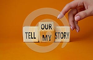 Tell our or my story symbol. Businessman hand points at turned wooden cubes with words Tell my story and Tell our story. Beautiful