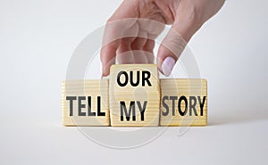 Tell our or my story symbol. Businessman hand turns wooden cubes and changes the words Tell my story to tell our story. Beautiful