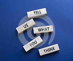 Tell us what you think symbol. Wooden blocks with words Tell us what you think. Beautiful deep blue background. Business and Tell