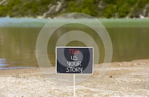 Tell us your story symbol. Concept word Tell us your story on beautiful black chalk blackboard. Beautiful mountain lake background