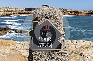 Tell us your story symbol. Concept word Tell us your story on beautiful black chalk blackboard. Beautiful red stone blue sea