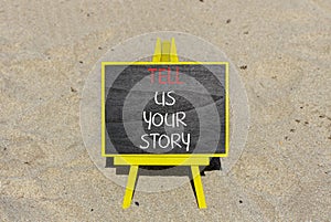 Tell us your story symbol. Concept word Tell us your story on beautiful black chalk blackboard. Beautiful sand beach background.