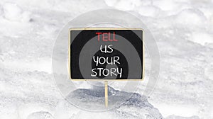 Tell us your story symbol. Concept word Tell us your story on beautiful black chalk blackboard. Beautiful white snow background.