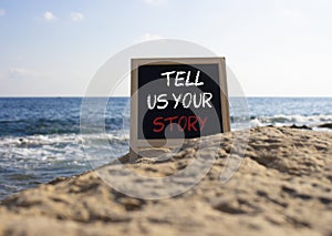 Tell us your story symbol. Concept words Tell us your story on black chalk blackboard. Beautiful sea background. Business and Tell