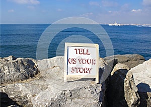 Tell us your story symbol. Concept words Tell us your story on white chalk blackboard. Beautiful sea background. Business and Tell