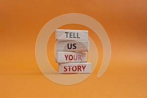 Tell us your story symbol. Concept words Tell us your story on wooden blocks. Beautiful orange background. Business and Tell us