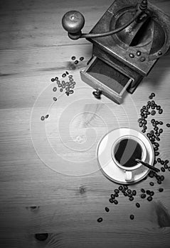 Telling story from the past - old vintage retro grinder with ground coffee and cup of black coffee with coffee beans top view