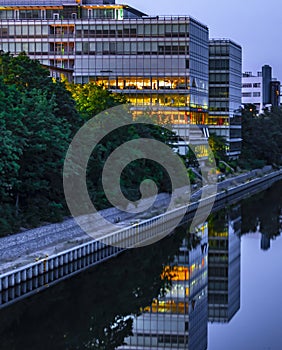 The Teltow Canal in Berlin-Tempelhof, Germany, with view to a modern office building. Some floors are colorful illuminated.