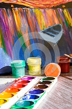 Tempera paints on the table in a workshop, selective focus, Set of watercolor paints, brushes for painting and palette