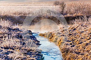 Temperature drop concept. Stream flows into river. Mist over water surface