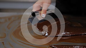 Tempering of the chocolate on the metal surface in the pastry shop.