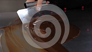 Tempering of the chocolate on the metal surface in the pastry shop.