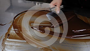 Tempering of the chocolate on the metal surface in the pastry shop.