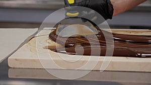 Tempering of the chocolate on the wooden surface.