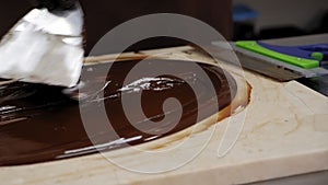 Tempering of the chocolate on the wooden surface.