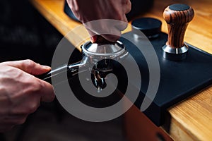 Tempering coffee in portafilter on a dark background photo