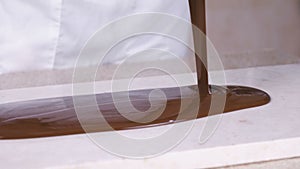 Tempering melted chocolate on natural stone. Woman`s hands and spatula close-up.