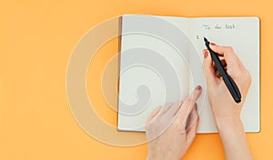 Template for design. Woman hand writes a to do list with a pen in a blank note pad