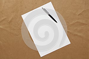 Template of white paper with pen lies diagonally on light brown cloth background. Concept of business plan and strategy