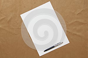 Template of white paper with pen lies diagonally on light brown cloth background. Concept of business plan and strategy