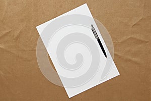 Template of white paper with pen lies diagonally on light brown cloth background. Concept of business plan and strategy