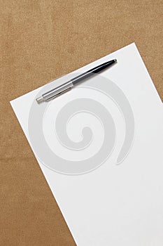 Template of white paper with pen lies diagonally on light brown cloth background. Concept of business plan and strategy