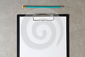 Template of white paper with simple pencil on light grey concrete background in a black tablet with a clip. Concept of new idea,