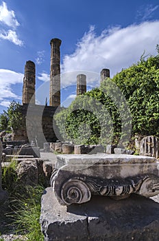 Temple of Apollo and a Ionic order capital of an ancient column at the archaeological site of Delphi.