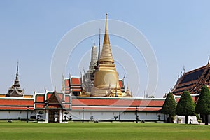 Temple of Emerald Buddha Wat Phra Kaew in Bangkok, Thailand with tree branches front isolated on blue sky background closeup.