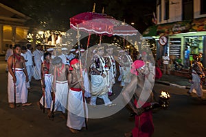 Temple priests and entourage walk along a street in Kandy at the completion of the Esala Perahera in Kandy, Sri Lanka.