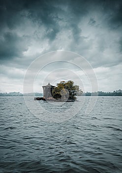 A temple in small island located in the middle of a river under heavy clouds. Dark blue Isolated island in a river