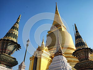 A temple in Thailand. The temple has a large golden stupa and several smaller ornate spires. Thai architecture