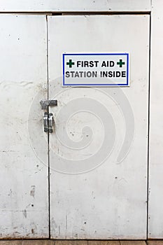 Temporary first aid station dirty white doors and sign at construction site.