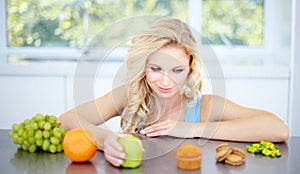 Temptation - Eat right and stay healthy. Pretty young woman being tempted to eat unhealthy food.