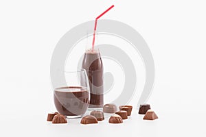 Tempting glass and bottle of chocolate milkshake with assorted chocolate sweets: Selective focus