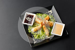 Tempura Deep Fried Shrimp Ebi with sweet chili and soy sauce on black board stone on dark background. Japanese food style