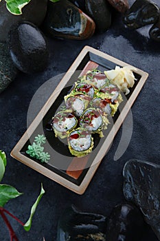 Tempura rolls with king prawns. Traditional Japanese food. Vertical photo on a black background. White ginger. Top view