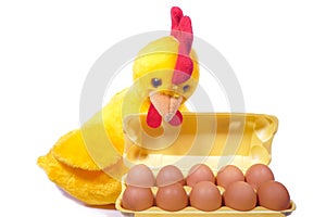 Ten chicken eggs in yellow box with toy rooster (white background)