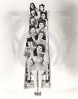 Ten chorus girls sitting on a ladder