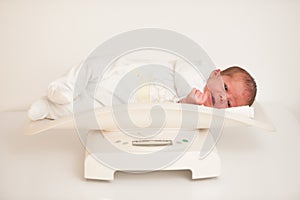 Ten days old new born child on a scale measuring weight