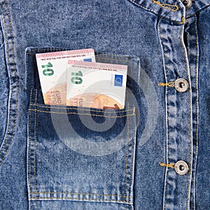 Ten euro notes in the pocket of blue jeans shirt.  European union money bills in jeans pocket, closeup