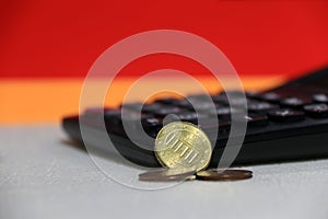 Ten Germany euro cent on obverse and two coin of two euro cent on white floor with black calculator, Red and yellow background.