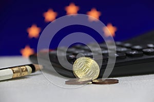 Ten Germany euro cent on obverse and two coin of two euro cent on white floor with black calculator and pencil, Euro flag.