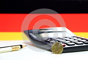 Ten Germany euro cent on obverse on white floor with black calculator and pencil, Germany flag background.